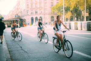 Tre donne in bicicletta in una strada urbana soleggiata