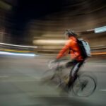 Ciclista in movimento che crea un effetto di sfocatura dinamica in una strada urbana illuminata di notte.