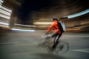 Ciclista in movimento che crea un effetto di sfocatura dinamica in una strada urbana illuminata di notte.