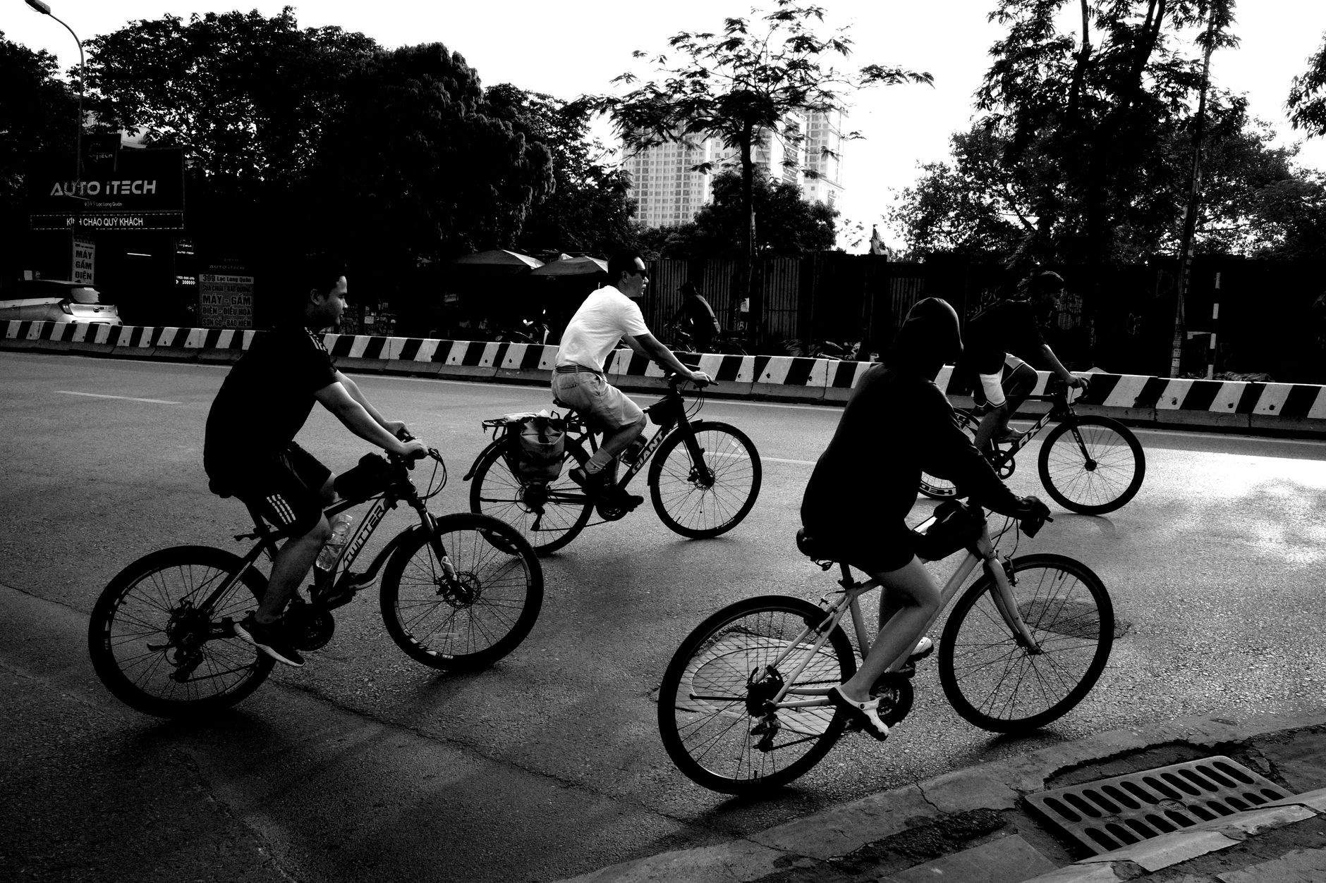 A group of people cycling on an urban road captured in a black and white photograph.