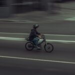 Ciclista in movimento sfocato su strada urbana, cattura la velocità e il flusso del traffico ciclistico in città