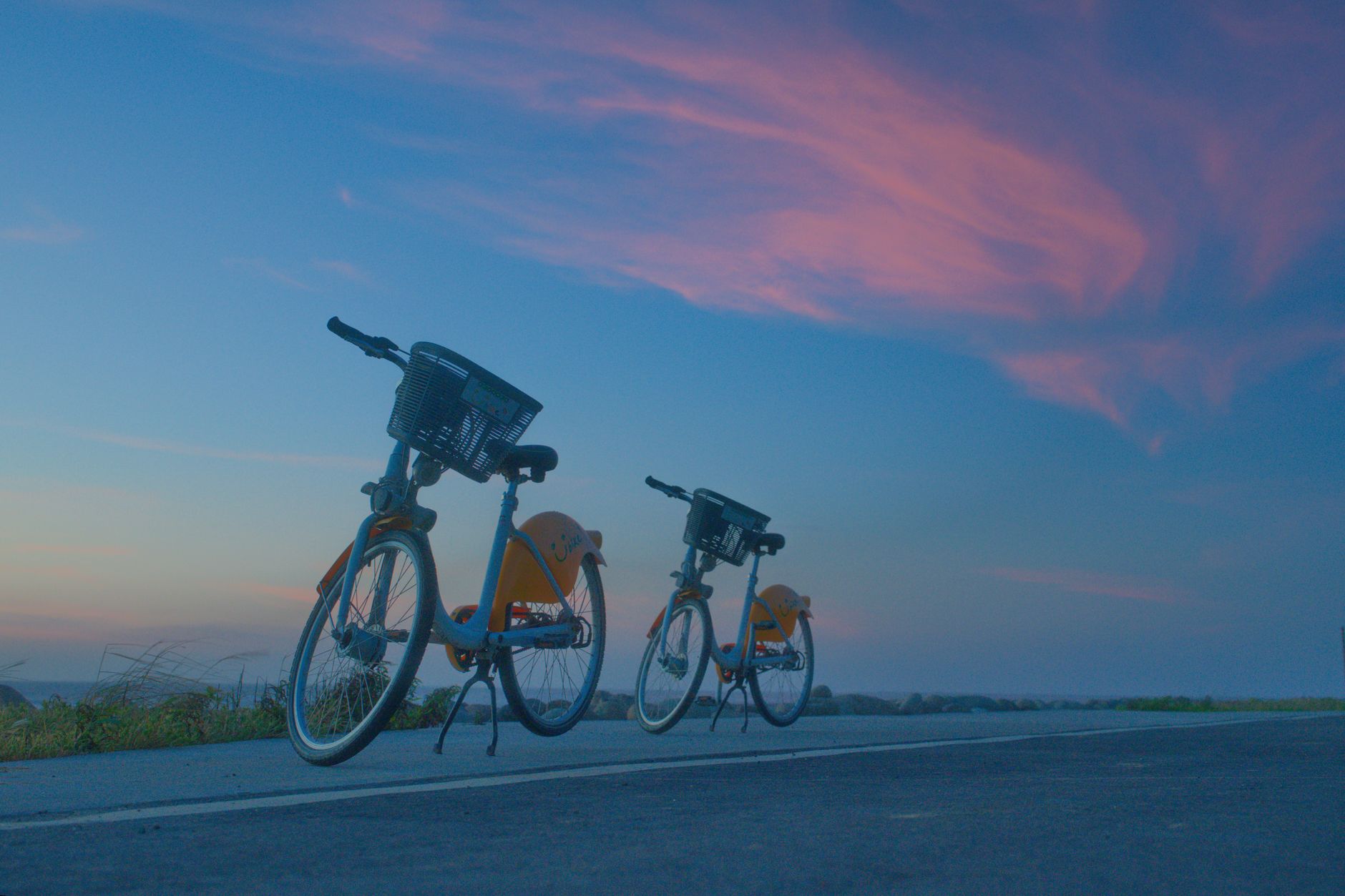 Due biciclette in sharing su una strada deserta al tramonto, l'orizzonte aperto davanti