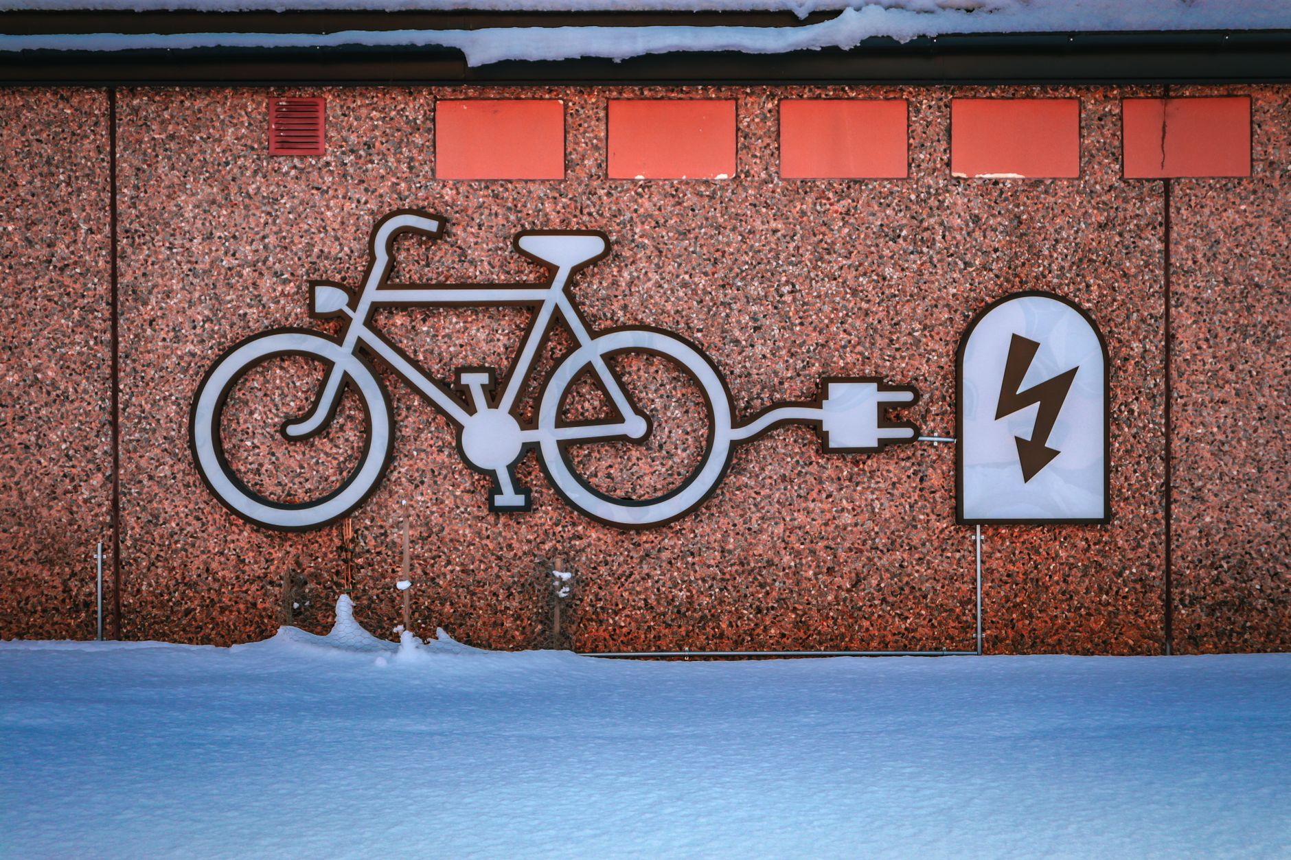 Grafica di ricarica e-bike su muro urbano innevato, simbolo di energia rinnovabile e mobilità elettrica